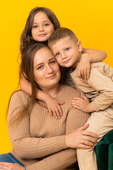 Fototapeta premium Caring mother with her children on a yellow background