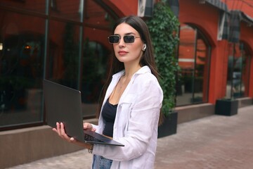 A freelance young woman works on a laptop in the office courtyard...