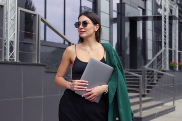 Portrait of a beautiful young woman with a laptop on the street