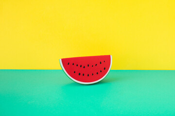 Rubber watermelon slice on turquoise and yellow background. Summer minimal concept.