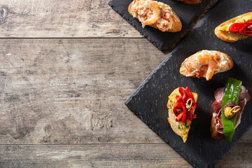 Assortment of Spanish pintxos on wooden table. Top view. Copy space