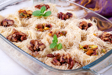 Kunafa dessert made of kataifi dough with pistachio and pecan nuts served in the glass dish. Egyptian cuisine