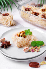 Kunafa dessert made of kataifi dough with pistachio and pecan nuts served on the plate. Egyptian cuisine