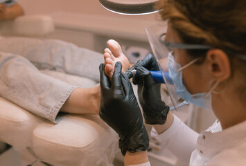 Chiropodist removes calluses in the beauty salon. Podiatry doctor. Treatment of feet and nails.
