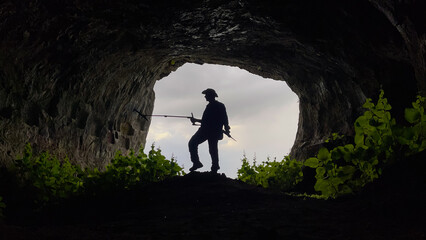treasure hunter with metal detector searching inside the cave in the historical texture