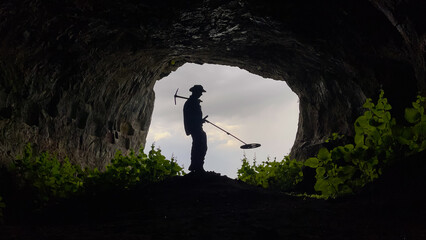 treasure hunter with metal detector searching inside the cave in the historical texture