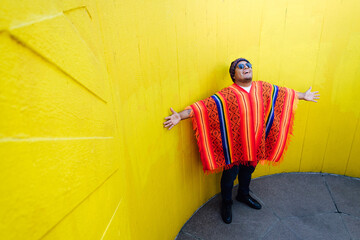Young man wearing Peruvian poncho looking up with his arms wide open - obrazy, fototapety, plakaty
