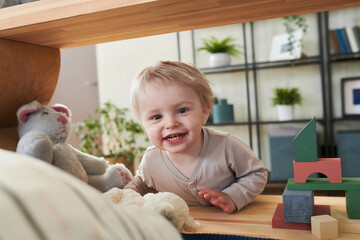 Portrait of adorable little kid smiling at camera during his game in the room