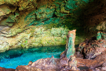 View of beautiful natural pool of crystal clear water formed in a rocky cave with stalagmites and stalagmites. Kuza cave in Zanzibar, Tanzania
