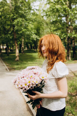 Red-haired curly girl with a bouquet of flowers