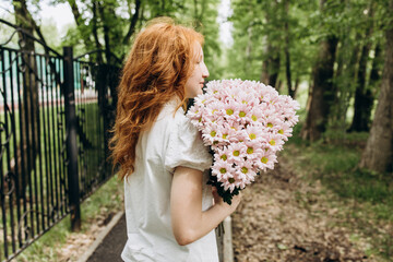 Red-haired curly girl with a bouquet of flowers