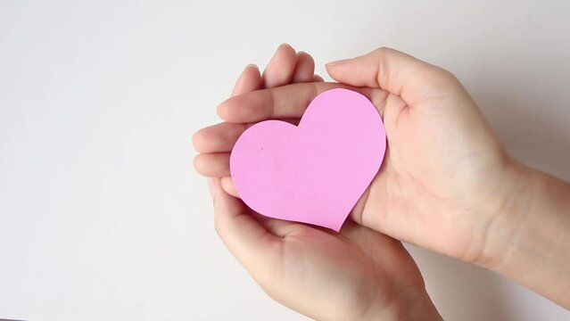 Hand holding pink heart on wood table background, healthcare, organ donation, love, hope and giving concept.