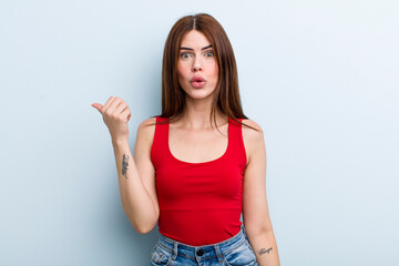young adult pretty woman looking astonished in disbelief, pointing at object on the side and saying...
