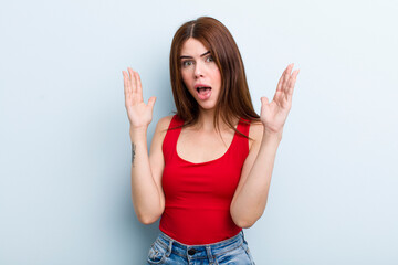 young adult pretty woman looking shocked and astonished, with jaw dropped in surprise when...