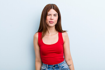 young adult pretty woman looking happy and friendly, smiling and winking an eye at you with a...