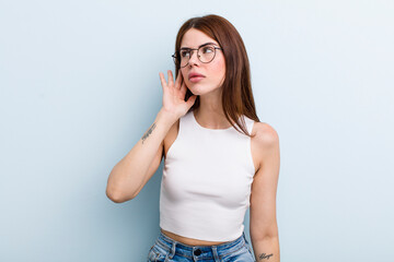 young adult pretty woman looking serious and curious, listening, trying to hear a secret...