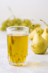 Juice of pears and grapes in a glass on a white wooden background