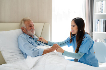 Obraz premium Professional female nurse is listening to breath of elderly man using stethoscope.