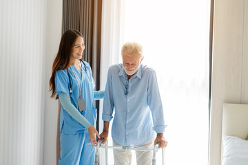 Care worker helping elderly man get out of bed and walk around the room.