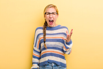 young adult  blonde woman looking angry, annoyed and frustrated screaming wtf or what’s wrong...