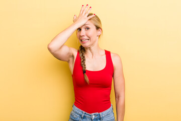 young adult  blonde woman raising palm to forehead thinking oops, after making a stupid mistake or remembering, feeling dumb - obrazy, fototapety, plakaty