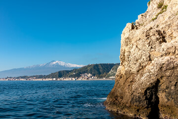 Touristic boat tour with panoramic view from open sea on snow capped volcano Mount Etna and the...