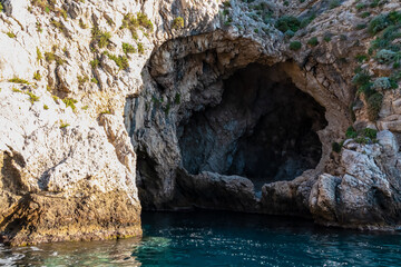 Entrance of sea cave Blue Grotto (Grotta Azzurra) near Isola Bella in Taormina, Sicily, Italy, Europe, EU. Clear magical blue turquoise water surface Ionian Mediterranean sea