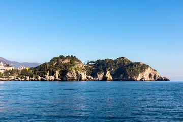 Fototapeta premium Panoramic view from the tourist island Isola Bella on the entrance of Blue Grotto (Grotta Azzurra) at Mediterranean coastline in Taormina, Sicily, Italy, Europe, EU. Calm water surface at Ionian sea