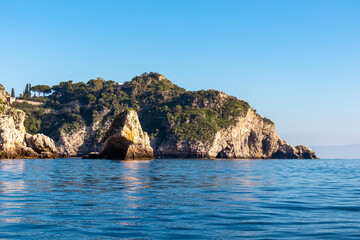 Fototapeta na wymiar Panoramic view from the tourist island Isola Bella on the entrance of Blue Grotto (Grotta Azzurra) at Mediterranean coastline in Taormina, Sicily, Italy, Europe, EU. Calm water surface at Ionian sea
