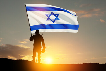 Silhouette of soldier with Israel flag against the sunrise in the desert. Concept - armed forces of...