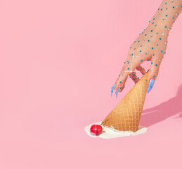 Summer creative layout with woman hand with sparkle stones reaching melting upside down ice cream cone with cherry on pastel pink background.  70s, 80s or 90s retro aesthetic fashion idea. 