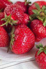 A white plate with fresh red strawberries close up.