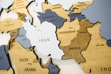 Iran, Afghanistan, Pakistan, Middle East on world map.  Wooden color multilayer world map on a white wall.