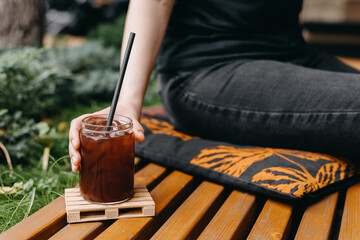 Woman holding a glass jar with cold brew coffee outdoors.
