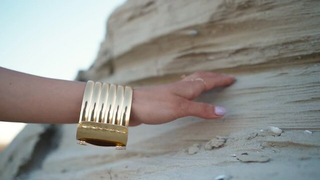 Beautiful female hand with an oriental gold bracelet on a background of sand. Jewelry concept.