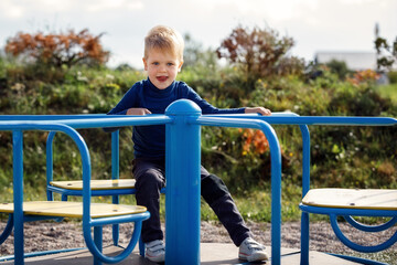 Little boy spinning on roundabout. Concept of child development, sports and education.