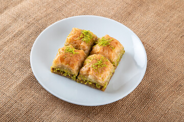 Pistachio baklava on a white plate.A plate baklava on fabric background
