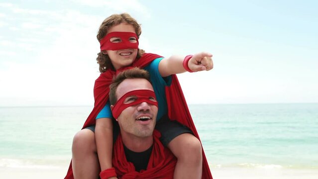 Animation of do it for them over happy caucasian father and son in superhero costumes on beach