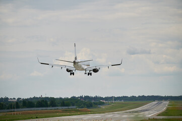 Commercial airplane flying in the sky at cloudy weather. Back view of airliner landing at the airport. Travel concept.