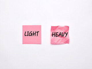 The words heavy and light on pink sheets of note paper.