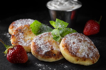 Cottage cheese pancakes with mint and sour cream, strawberries and powder