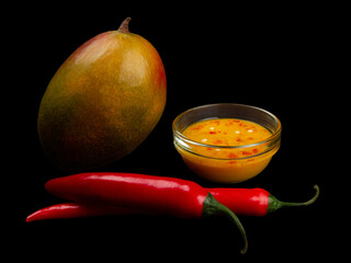 Mango, chili and mango chili sauce on black background. Side view