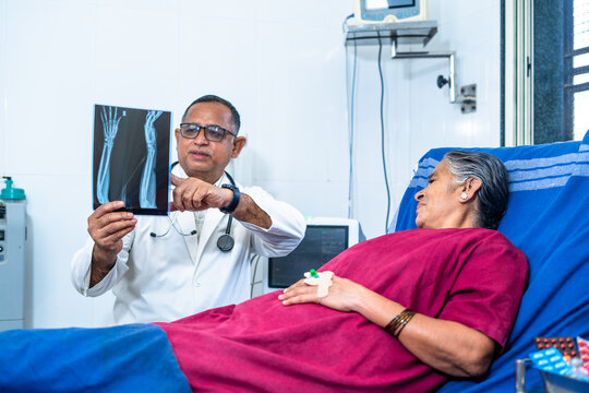 Doctor explaining from x-ray report to senior patient at hospital before surgery - concept of medical, healthcare treatment and friendly surgeon.
