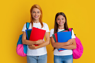 School, learning and education concept. Mother and daughter schoolgirls with school backpack and books ready to learn. Back to school. Mom and child on isolated yellow studio background.
