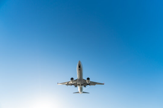 Close-up view from below of a departing plane with landing gear on a blue sky background on a sunny day, copy space