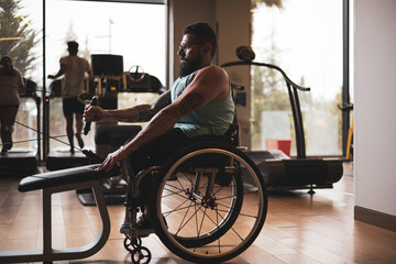 A person in a wheelchair training in a gym, working the lats. Concept of motivation in sport.