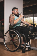 Fototapeta na wymiar A person in a wheelchair training in a gym, working the lats. Concept of motivation in sport.
