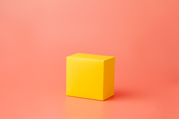 Yellow cube made of paper or cardboard. Geometric figure isolated on a pink background.