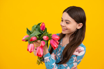 Obraz na płótnie Canvas Teenager child girl with bouquet of tulips on yellow studio background. Girl enjoying flowers.