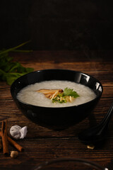 Traditional Chinese porridge rice in bowl with soft boiled egg, shiitake mushroom, slice ginger and slice scallion.
